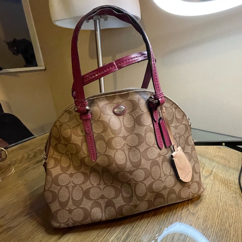 Tan monogram coach handbag with shoulder strap. Pie-loved wear on handles